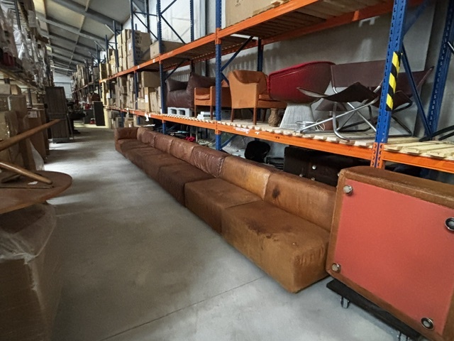 Magazijnopstelling met lange vintage modulaire bank en designmeubels